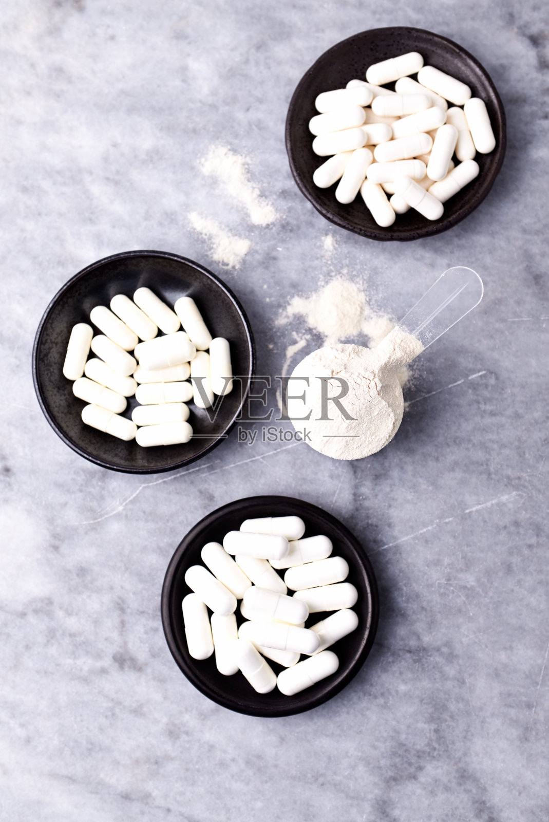 乳清蛋白,水解膠原I型,l -脯氨酸和l -賴氨酸膠囊勺。補充膠原蛋白的生產(chǎn)。明亮的石頭背景。直接上圖。副本的空間。